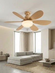 A modern five-blade ceiling fan with light wood blades and a frosted glass light fixture, installed in a bright, contemporary living room with a gray sectional sofa and beige curtains. #color_Natural Oak